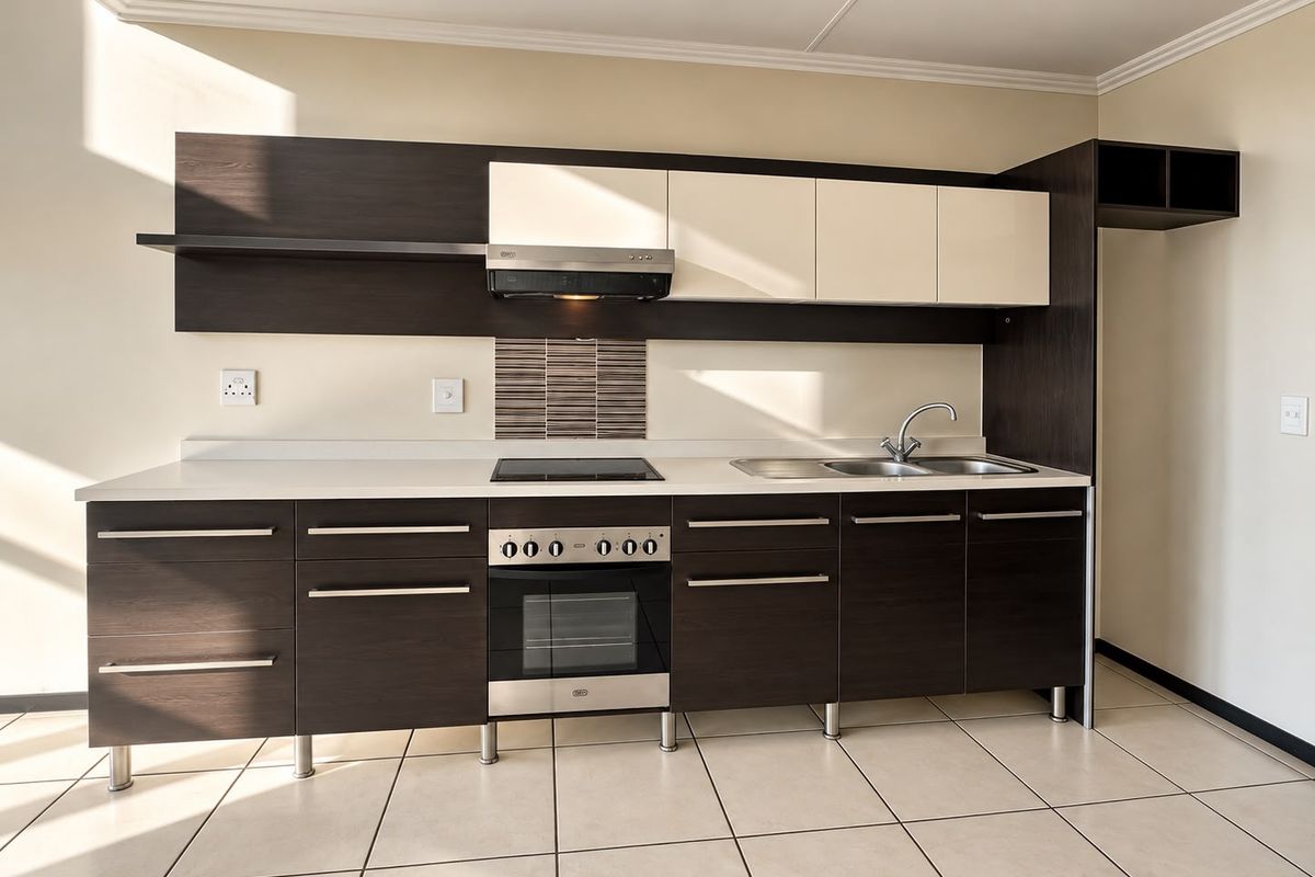 Modern kitchen featuring dark wood and cream cabinetry, integrated electric hob and oven, stainless steel sink, and neutral tiled flooring.