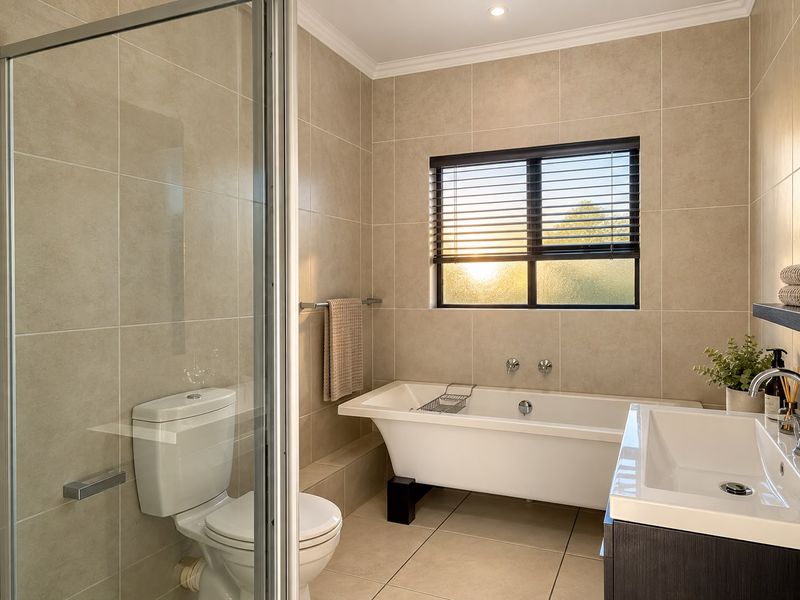 Modern bathroom featuring a freestanding bathtub, glass-enclosed shower, wall-mounted toilet, and a sleek vanity basin with neutral floor-to-ceiling tiling.