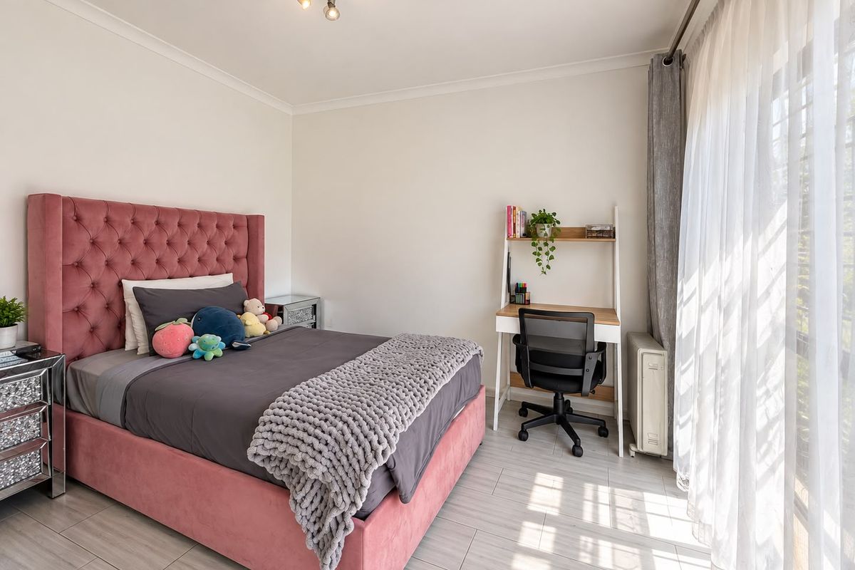 A bright and well-maintained bedroom featuring tiled flooring, neutral walls, and a large sliding glass door that provides ample natural light.
