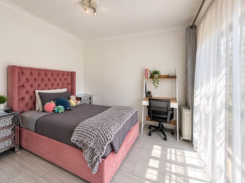 A bright and well-maintained bedroom featuring tiled flooring, neutral walls, and a large sliding glass door that provides ample natural light.