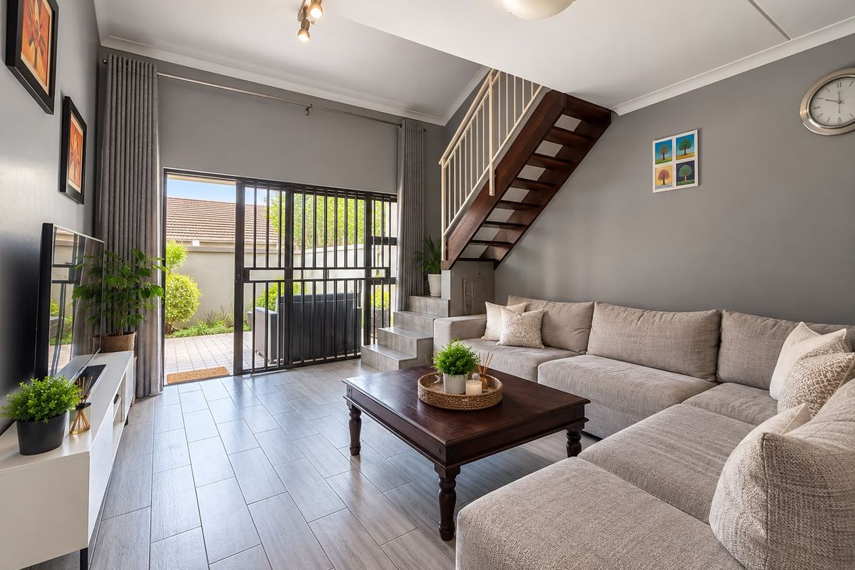 A well-maintained living room featuring tiled floors, a staircase, and sliding glass doors that provide direct access to the outdoor patio area.