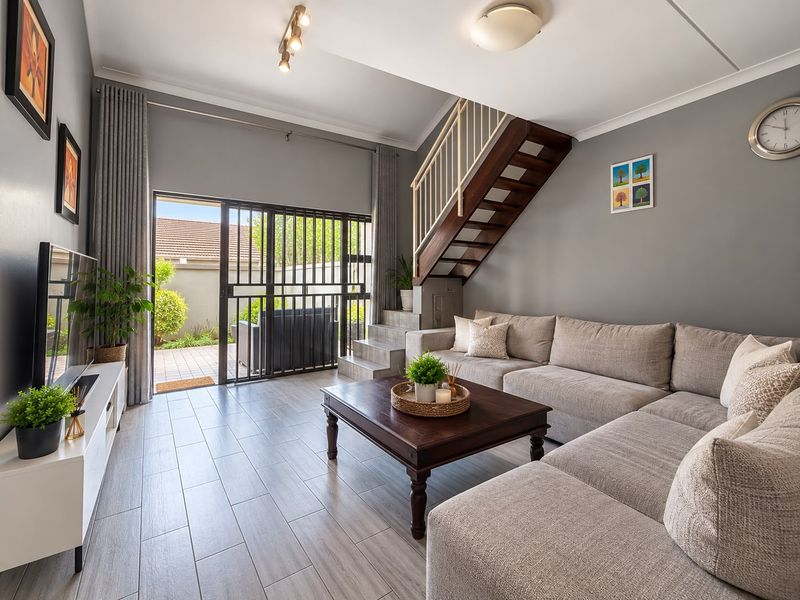 A well-maintained living room featuring tiled floors, a staircase, and sliding glass doors that provide direct access to the outdoor patio area.