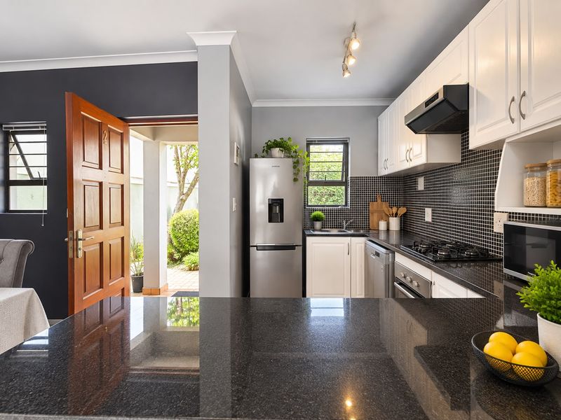 Modern kitchen featuring granite countertops, mosaic tile backsplash, built-in oven, gas hob, and direct access to an outdoor patio area.