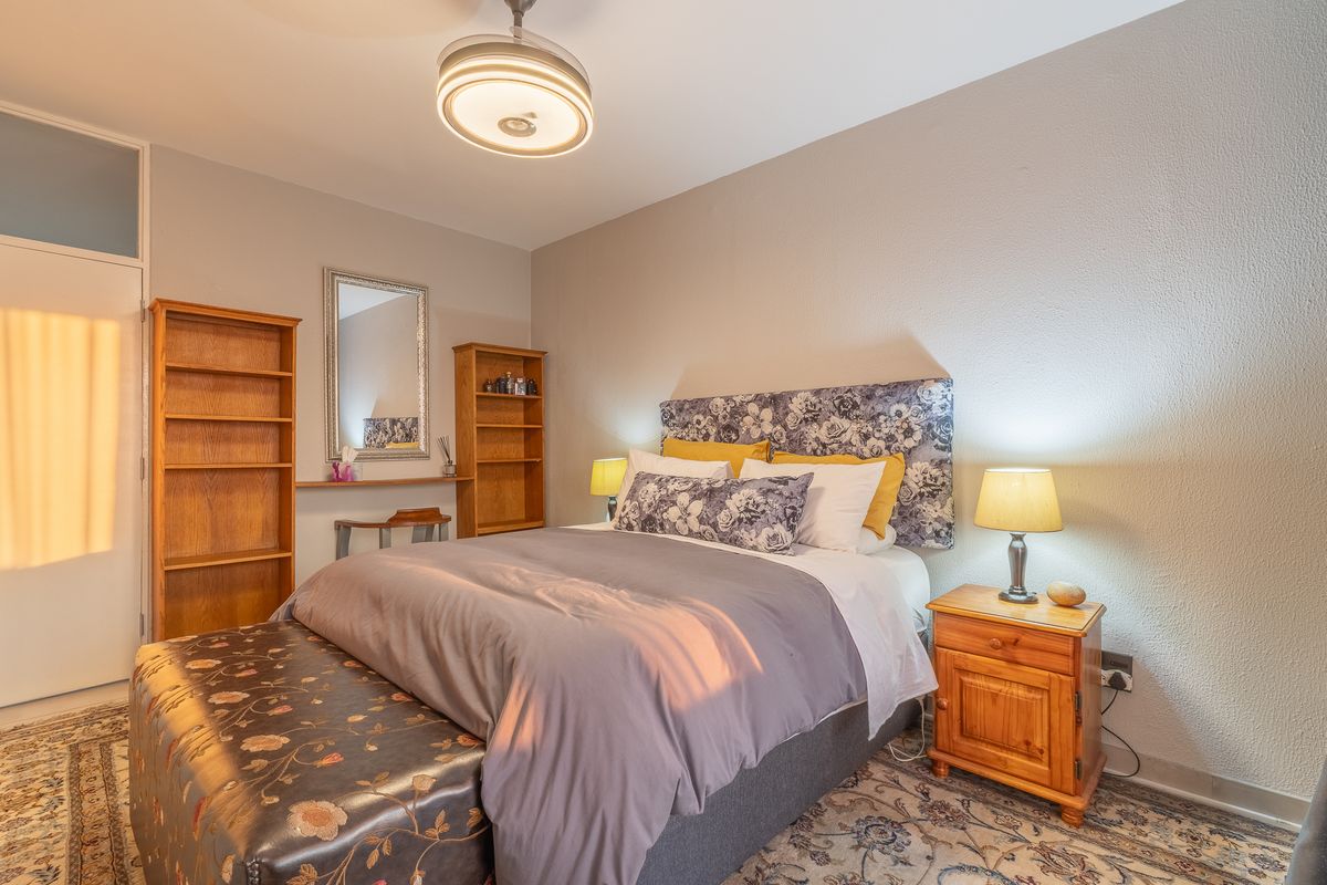 A well-lit bedroom featuring built-in shelving units, a ceiling light fixture, and a built-in cupboard, offering functional storage and a comfortable living space.