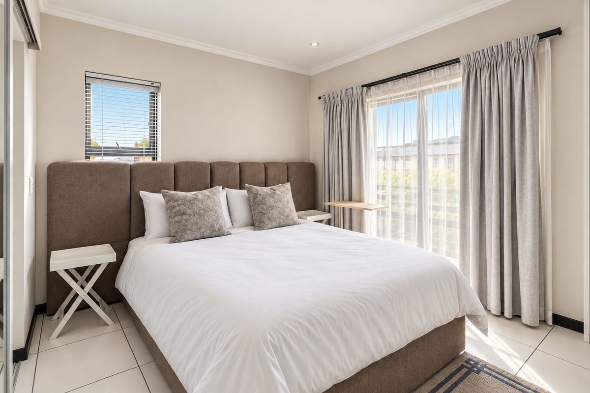 A well-maintained bedroom featuring tiled flooring, recessed downlights, and a sliding glass door providing access to an outdoor area.