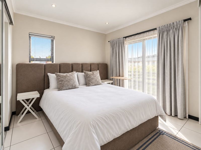 A well-maintained bedroom featuring tiled flooring, recessed downlights, and a sliding glass door providing access to an outdoor area.