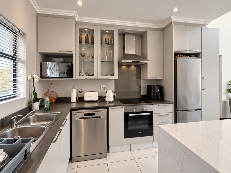 Modern kitchen featuring sleek cabinetry, stone countertops, integrated stainless steel appliances, and a functional layout with ample storage and recessed lighting.