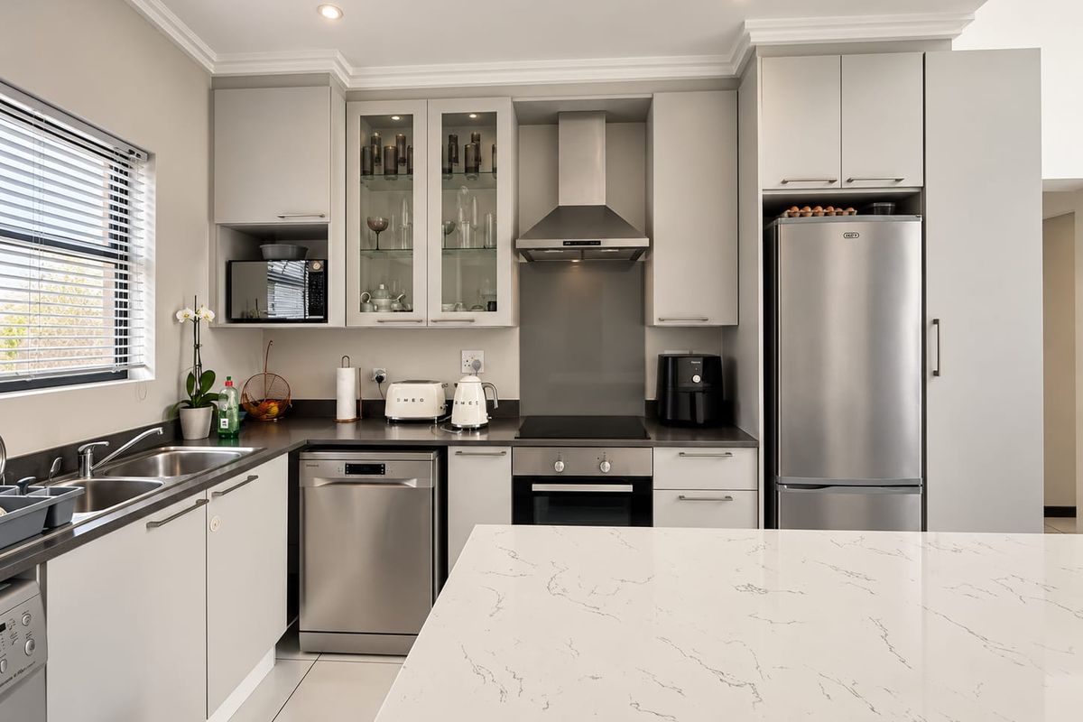 Modern kitchen featuring sleek light grey cabinetry, stone countertops, stainless steel appliances, and a functional layout with ample storage and recessed lighting.