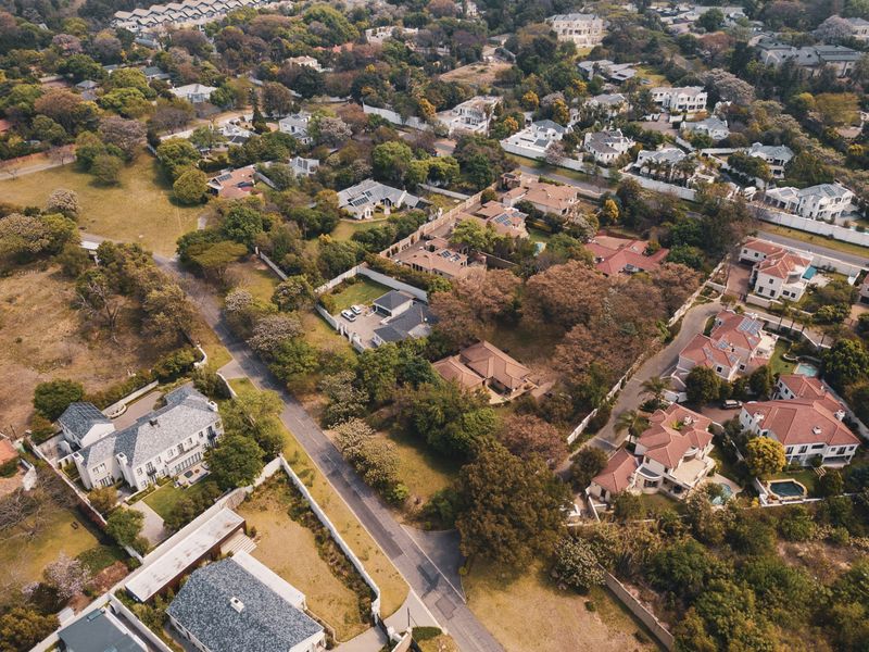 An aerial view of a well-established residential neighborhood featuring mature trees, paved roads, and various detached homes within a suburban setting.