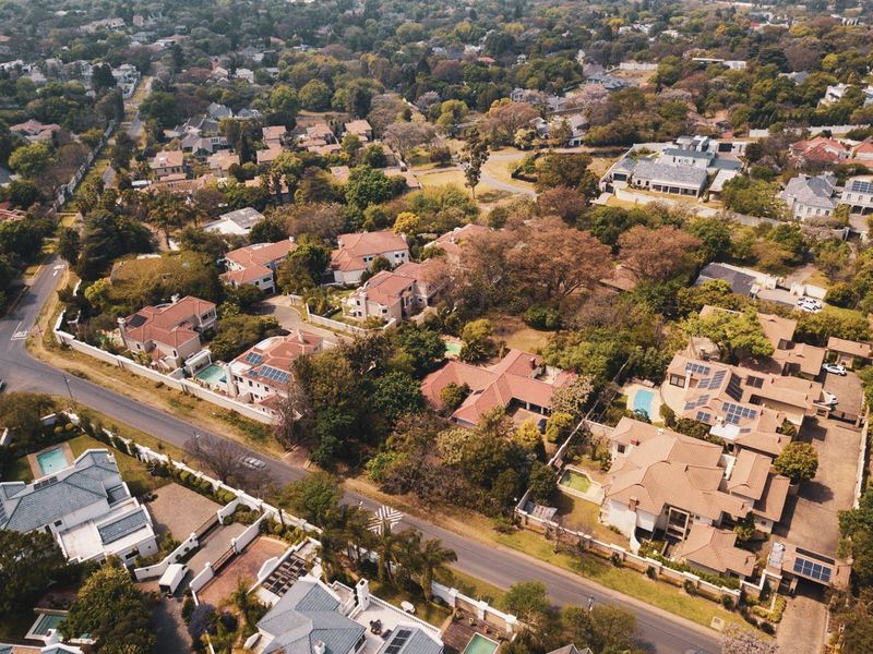 An aerial view of a well-established residential neighborhood featuring numerous homes with tiled roofs, swimming pools, and mature landscaping.