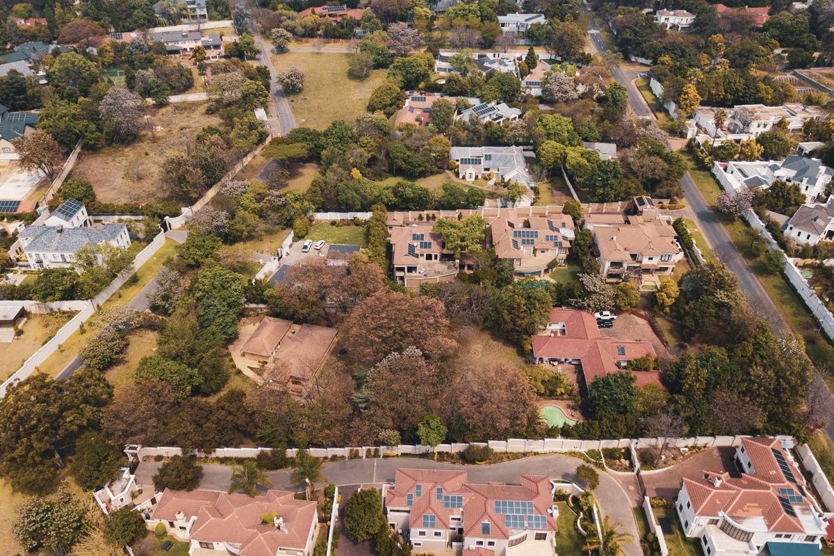 An aerial view of a well-established residential neighborhood featuring mature trees, paved streets, and various detached housing properties.