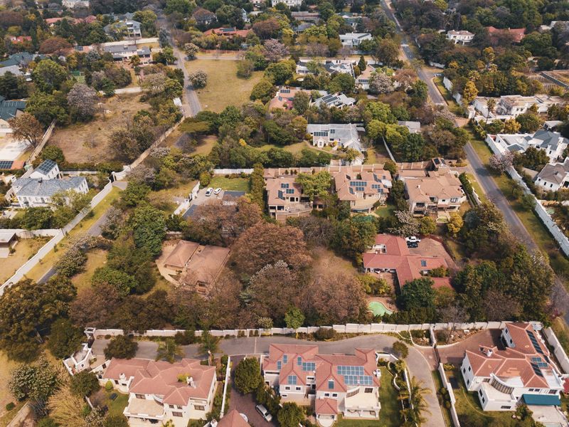 An aerial view of a well-established residential neighborhood featuring mature trees, paved streets, and various detached housing properties.