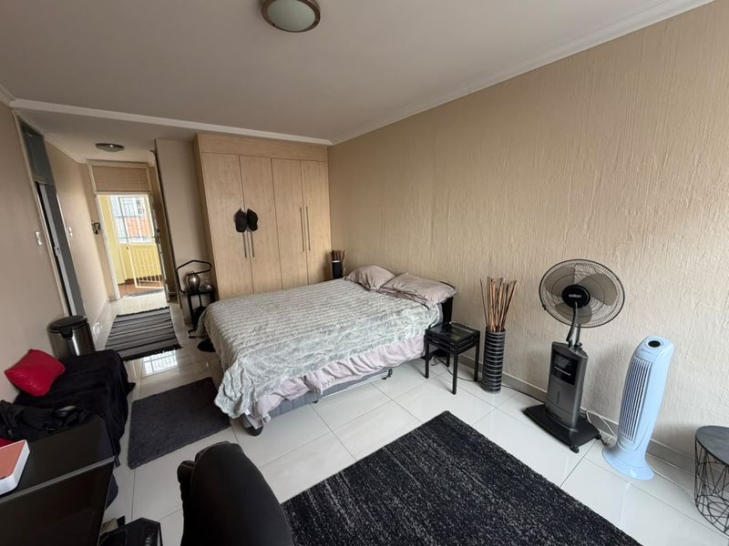 A bedroom featuring built-in cupboards, tiled flooring, and access to an adjoining balcony area.