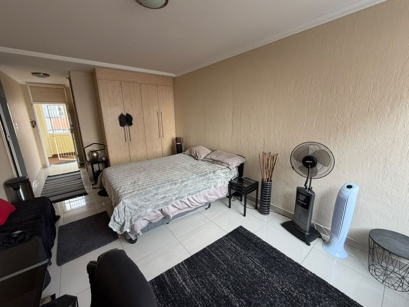 A bedroom featuring built-in cupboards, tiled flooring, and access to an adjoining balcony area.