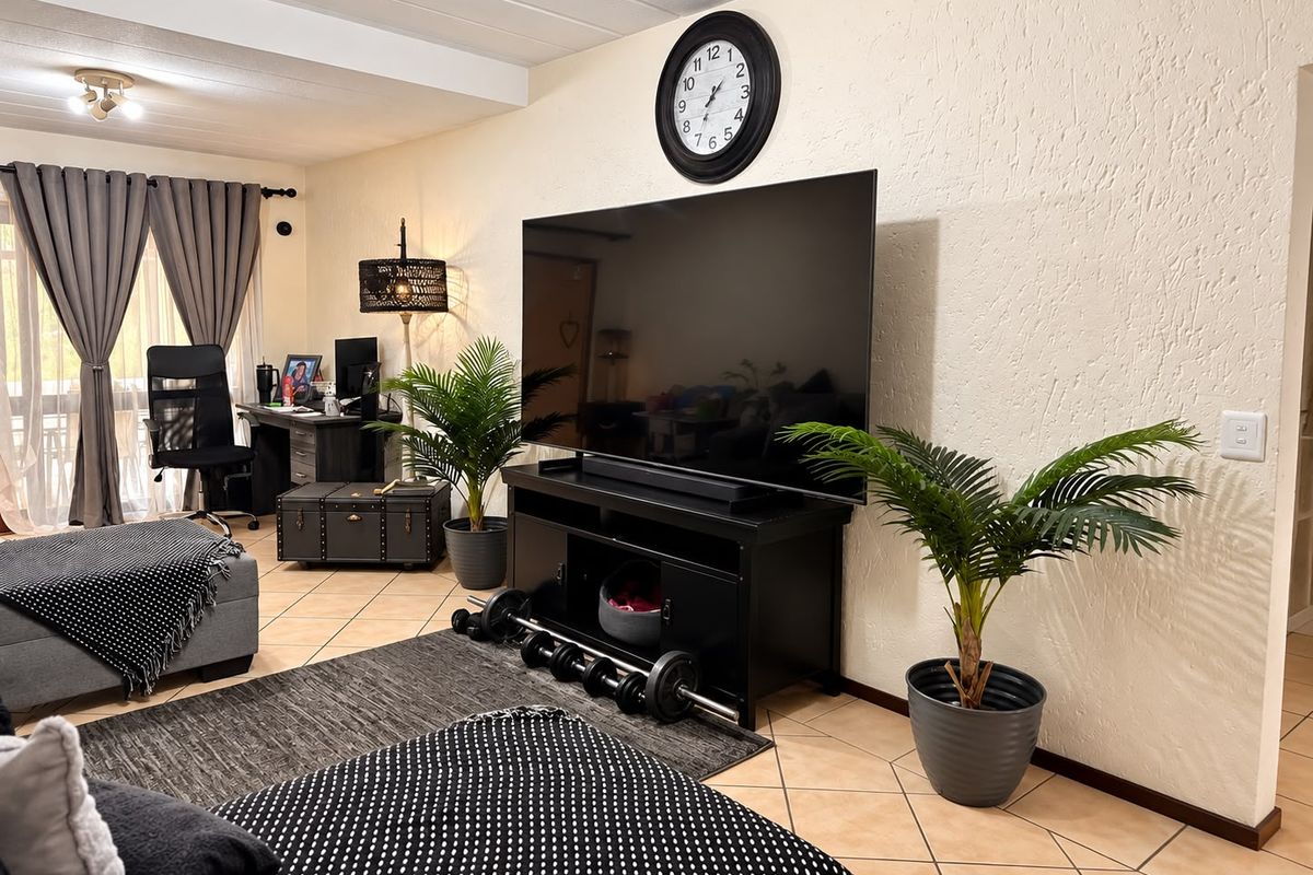 A comfortable living room featuring tiled flooring, textured walls, and a sliding glass door providing access to the outdoor area.
