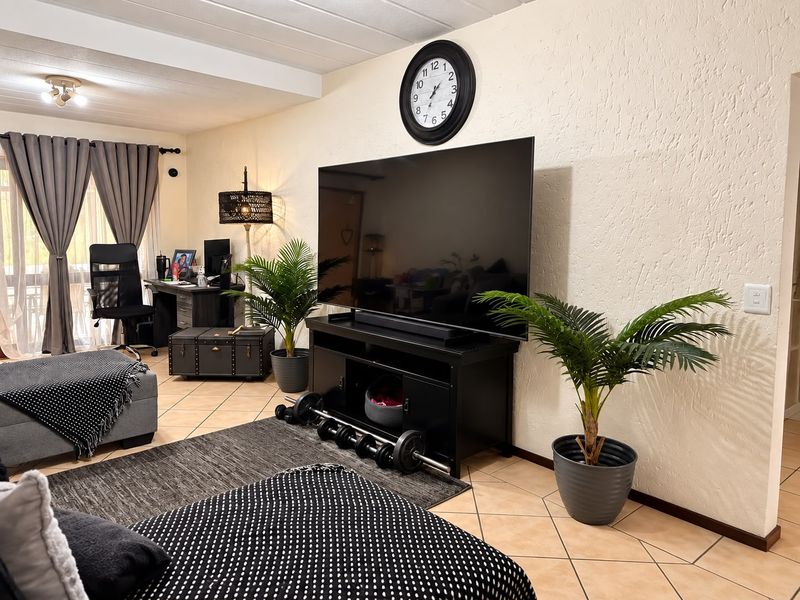 A comfortable living room featuring tiled flooring, textured walls, and a sliding glass door providing access to the outdoor area.