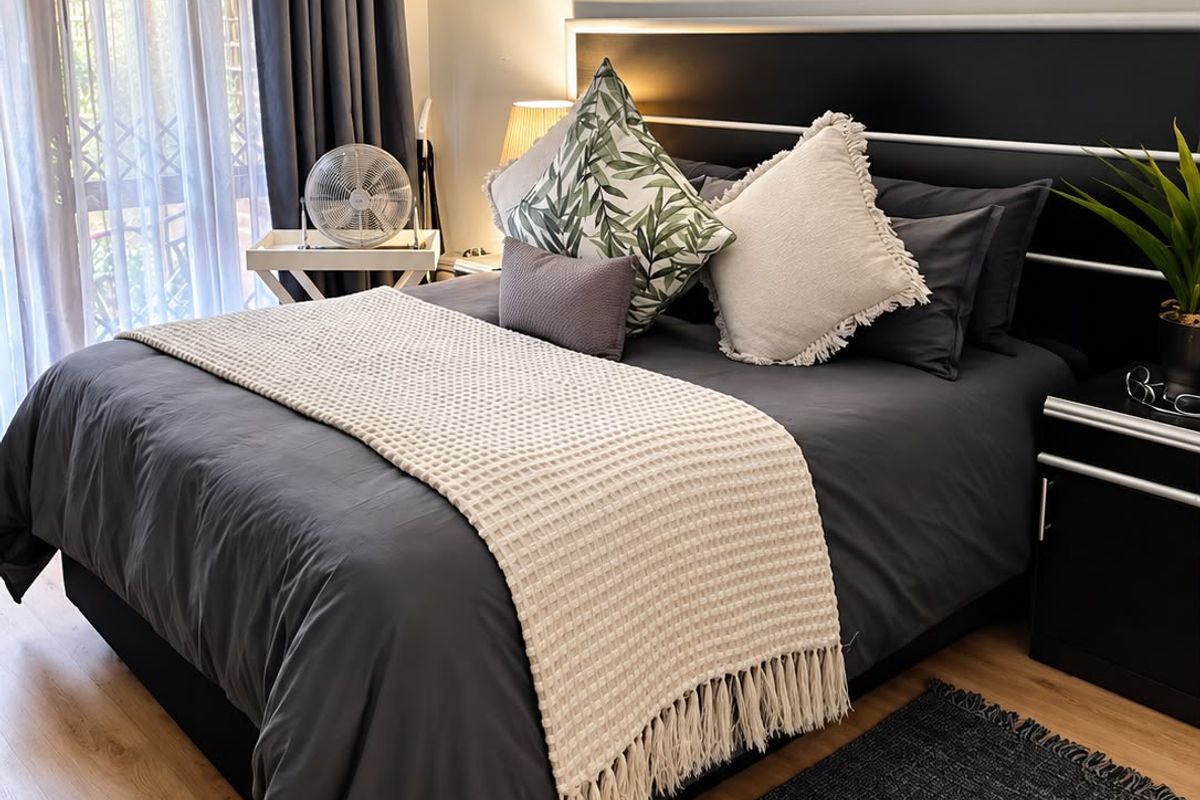 A well-maintained bedroom featuring laminate flooring and a sliding door with an integrated security gate, providing access to an outdoor area.