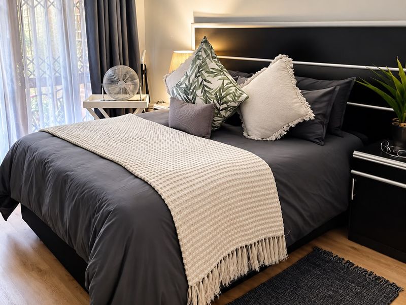 A well-maintained bedroom featuring laminate flooring and a sliding door with an integrated security gate, providing access to an outdoor area.