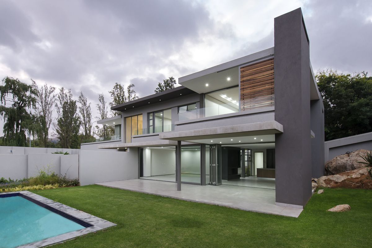 Modern double-storey cluster home featuring a spacious covered patio, swimming pool, and contemporary architectural finishes with large glass sliding doors.