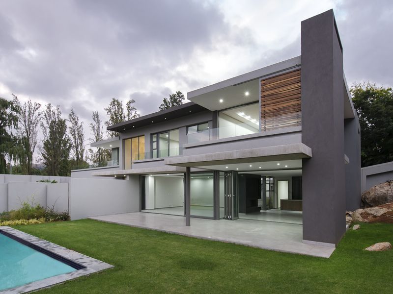 Modern double-storey cluster home featuring a spacious covered patio, swimming pool, and contemporary architectural finishes with large glass sliding doors.