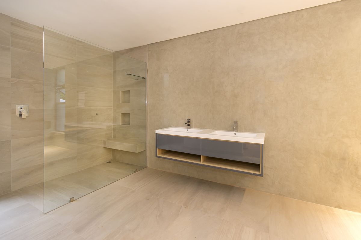 Modern bathroom featuring a spacious walk-in shower with built-in bench and niches, alongside a sleek wall-mounted double vanity with contemporary finishes.