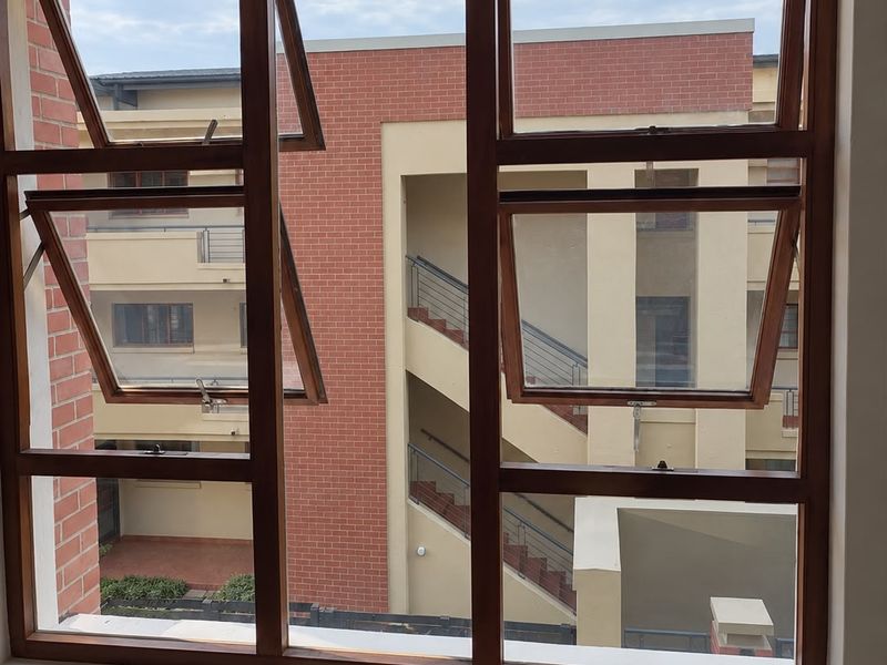 A view from an interior window looking out onto the brick facade and stairwell of an adjacent apartment building.