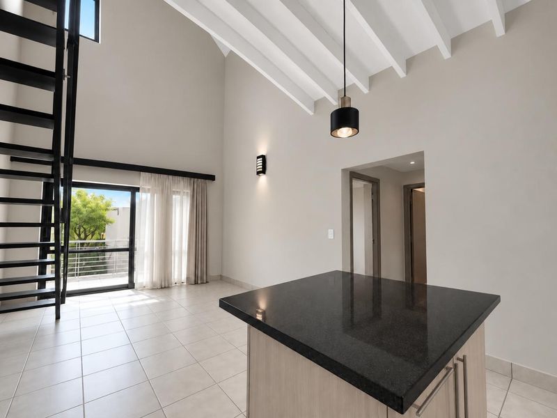 Spacious open-plan living area featuring high vaulted ceilings with exposed beams, a modern black metal staircase, and a sleek kitchen island with granite countertop.