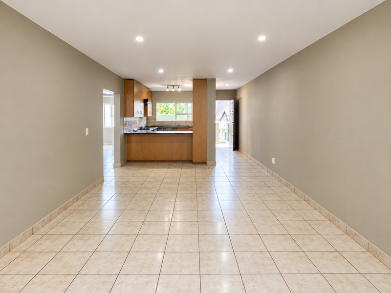 Spacious open-plan living and kitchen area featuring neutral wall tones, tiled flooring, and recessed lighting, offering a clean and versatile layout.