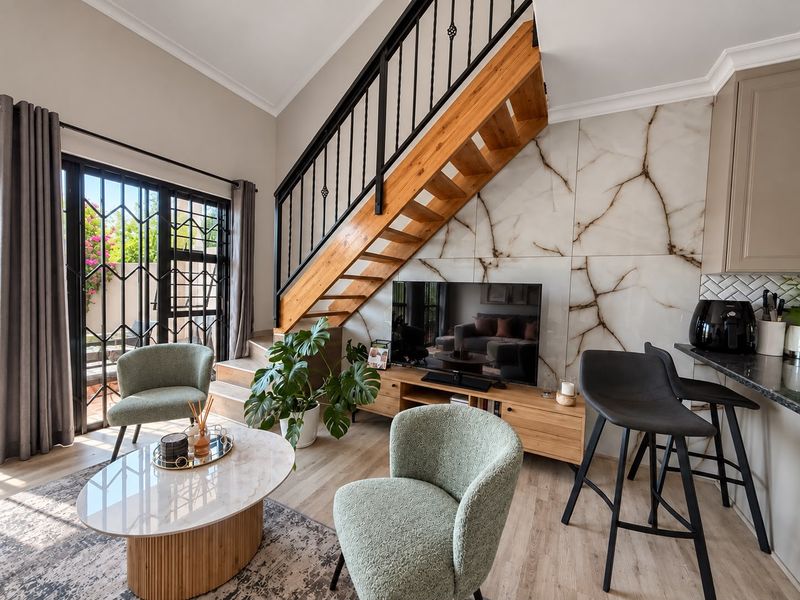Modern open-plan living area featuring a striking marble-look feature wall, wooden staircase with iron balustrade, and seamless access to the outdoor patio.