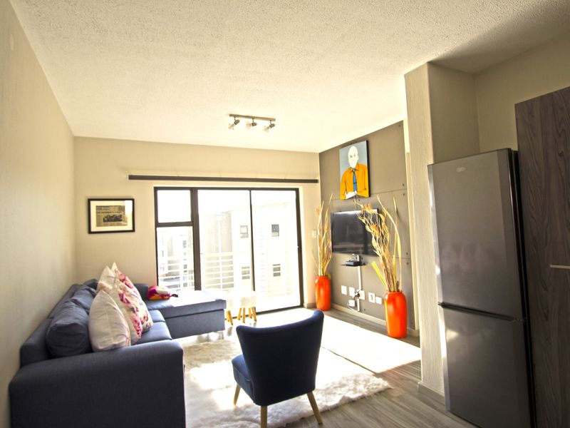 Open plan living area featuring laminate flooring, an accent wall, and a sliding glass door providing access to the balcony.