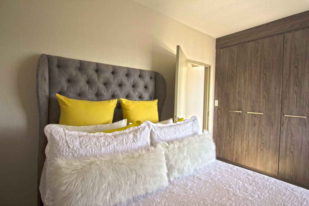 A well-maintained bedroom featuring a built-in wardrobe with wood-grain finish doors.