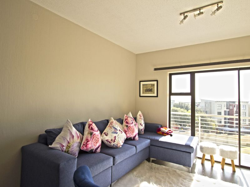 A bright living room featuring a large sliding glass door that opens onto a balcony, providing natural light and exterior views.