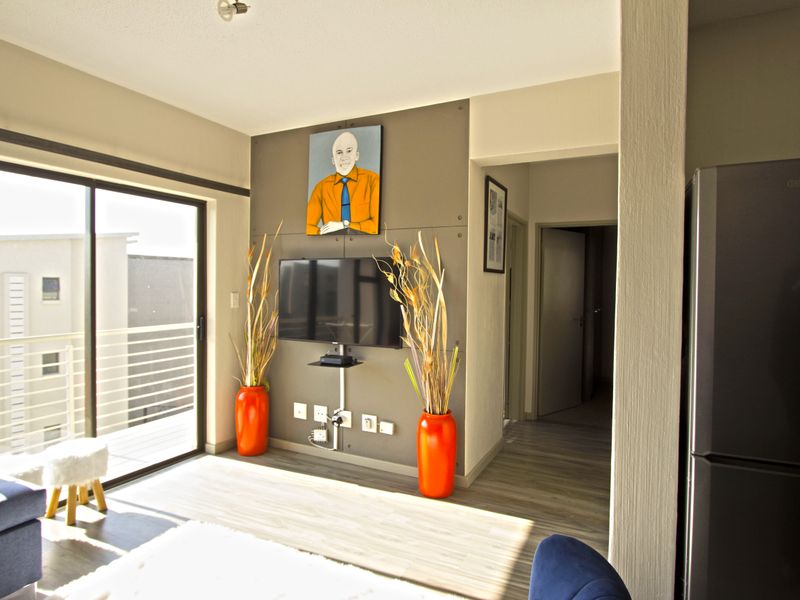 A bright living area featuring laminate flooring, a textured feature wall, and a large sliding glass door leading to an outdoor balcony.
