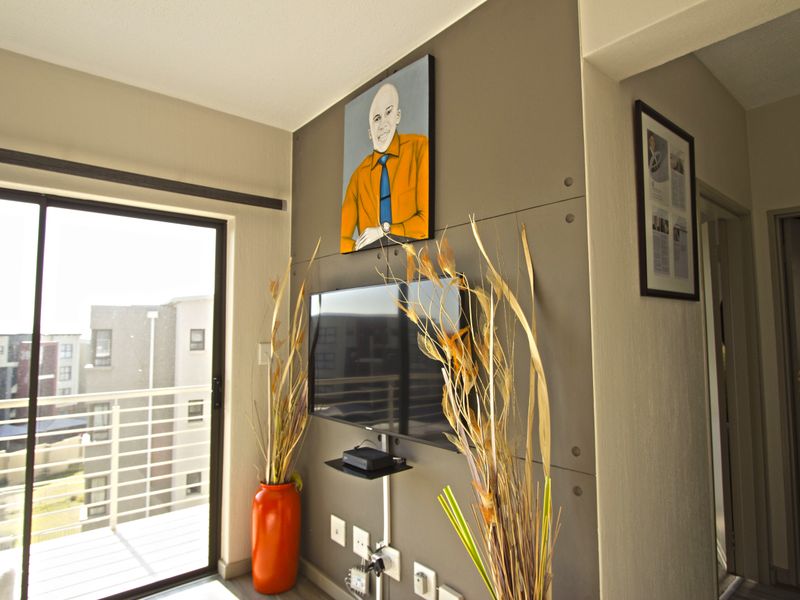 A living room area featuring a modern grey feature wall, sliding glass door access to a balcony, and integrated electrical fixtures.
