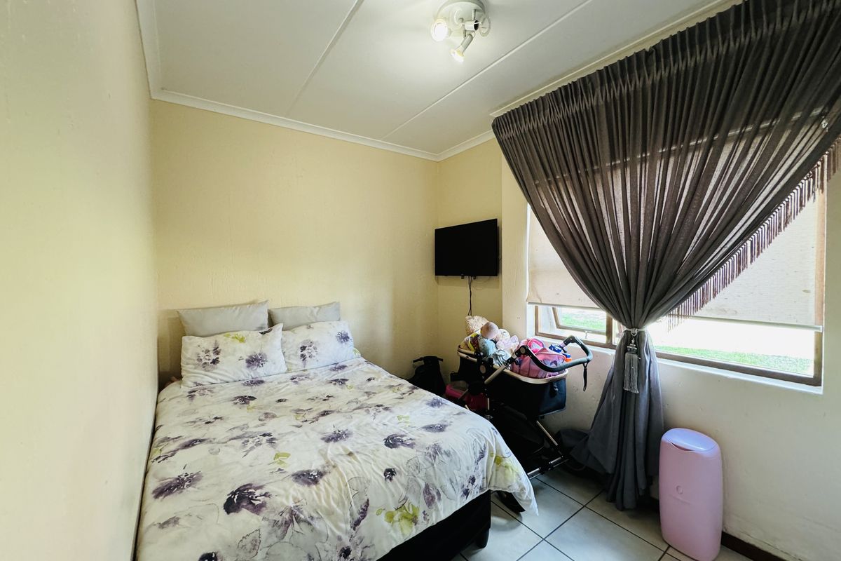A functional bedroom featuring tiled flooring and a ceiling-mounted light fixture, providing a neutral space ready for personalization.