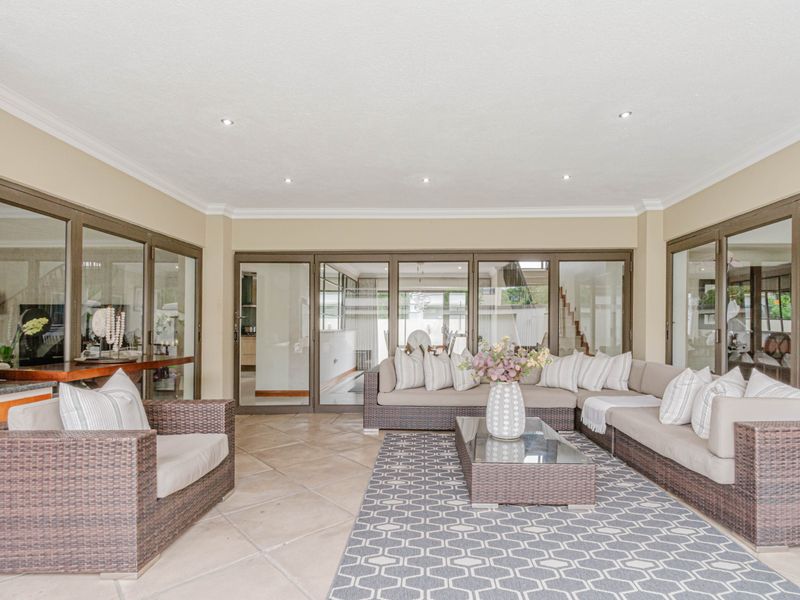 A spacious covered patio featuring tiled flooring, recessed downlights, and large aluminium sliding doors that provide seamless access to the interior living areas.