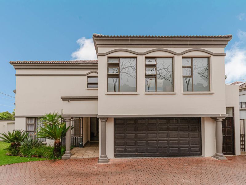 Front elevation of a double-storey cluster home featuring a paved driveway, double garage, and classic architectural detailing with neutral exterior finishes.