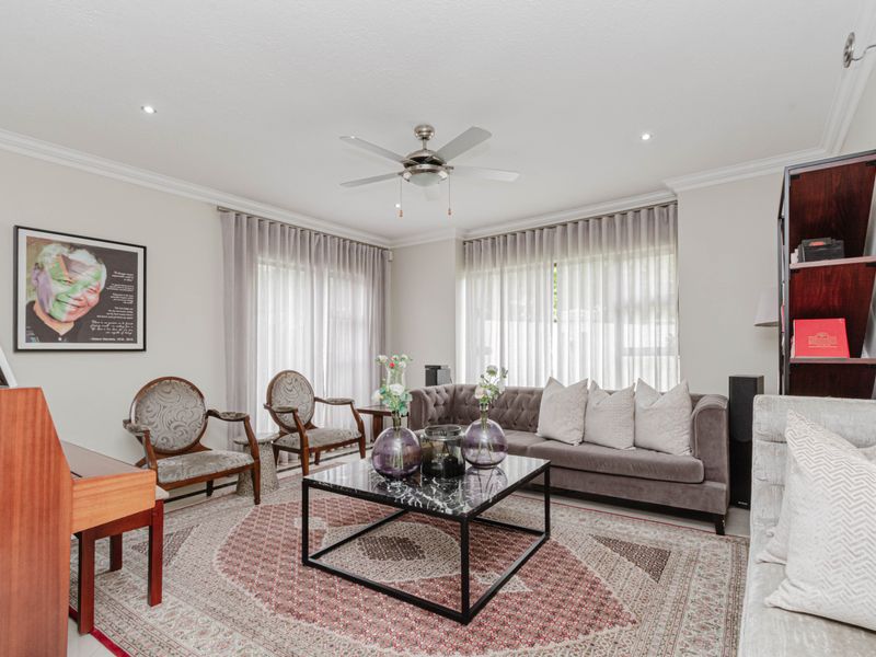 A well-maintained living room featuring crown molding, recessed lighting, and a central ceiling fan, offering a bright and comfortable space.