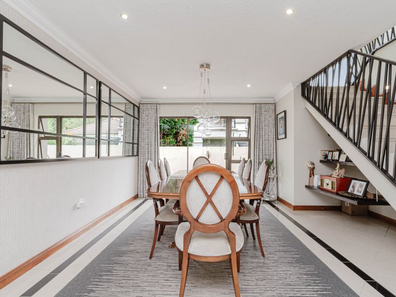 Elegant dining room featuring tiled floors with decorative borders, a striking wrought iron staircase, and large sliding doors leading to the exterior.