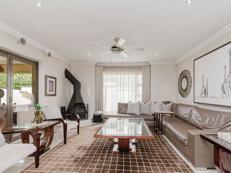 A well-maintained living room featuring a modern freestanding fireplace, ceiling fan, recessed lighting, and large sliding glass doors leading to an outdoor area.