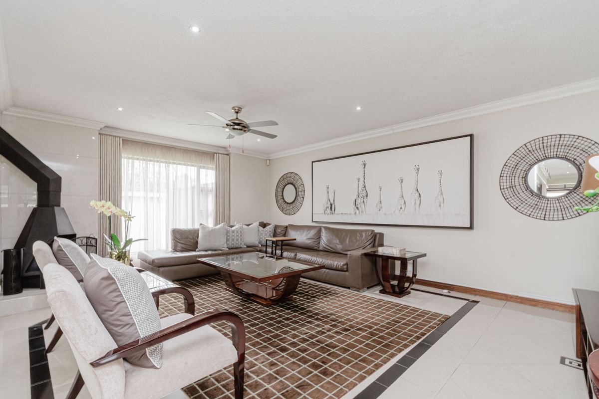 Spacious living room featuring tiled flooring, recessed lighting, a ceiling fan, and a modern corner fireplace with access to the patio.