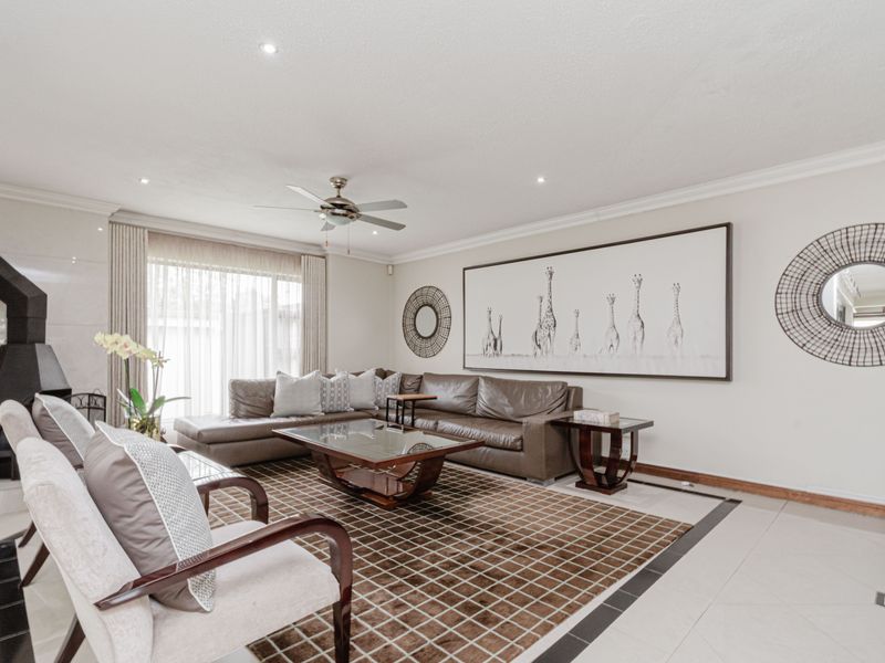 Spacious living room featuring tiled flooring, recessed lighting, a ceiling fan, and a modern corner fireplace with access to the patio.