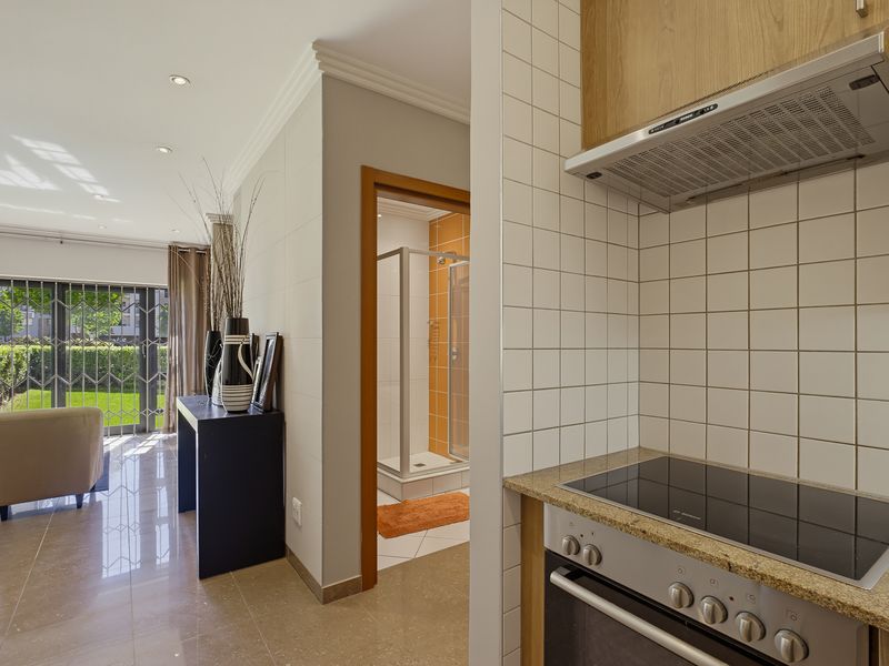 Open-plan living area featuring a modern kitchen with granite countertops, built-in oven and hob, leading to a bright lounge and adjacent bathroom.