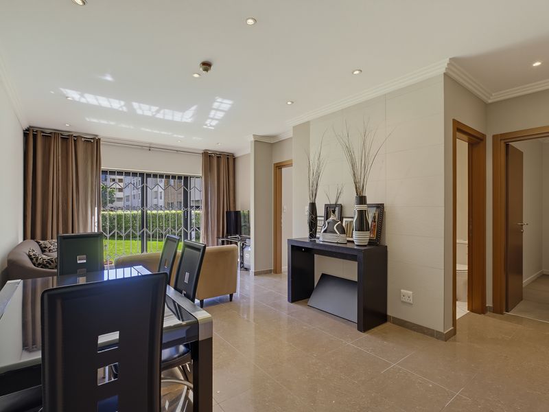 Spacious open-plan living and dining area featuring tiled floors, recessed lighting, and direct access to an outdoor space through a secure sliding door.