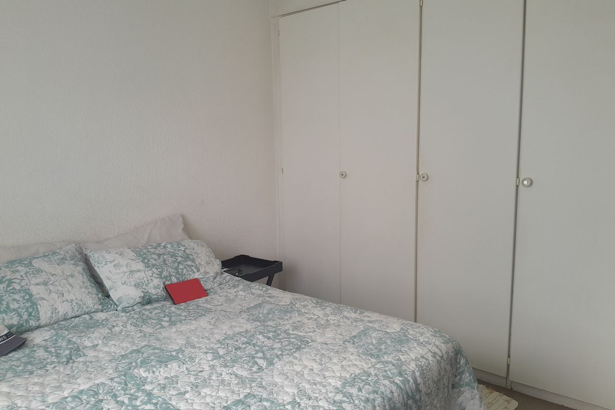 A bedroom featuring built-in cupboards with white doors and textured wall finishes.