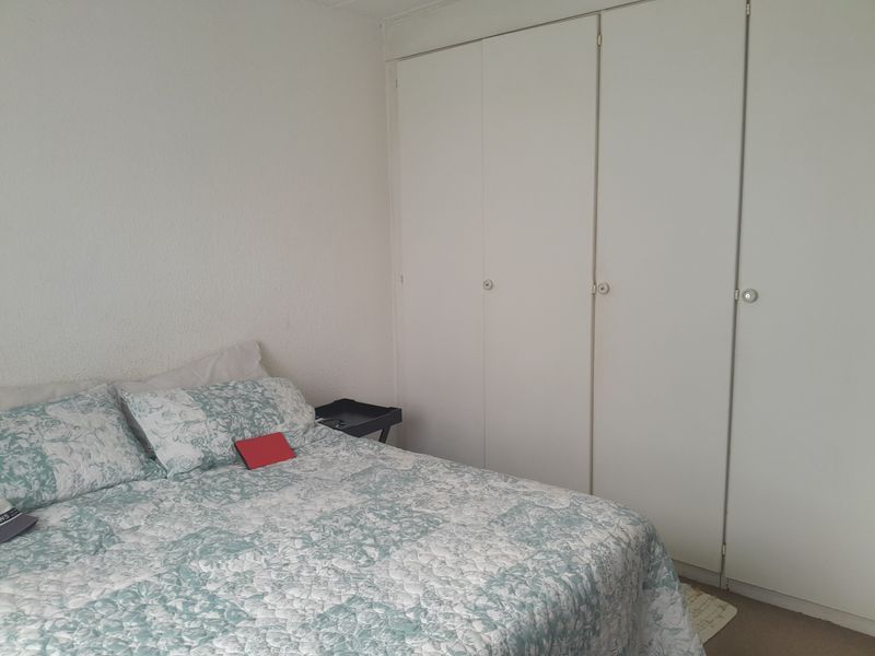 A bedroom featuring built-in cupboards with white doors and textured wall finishes.