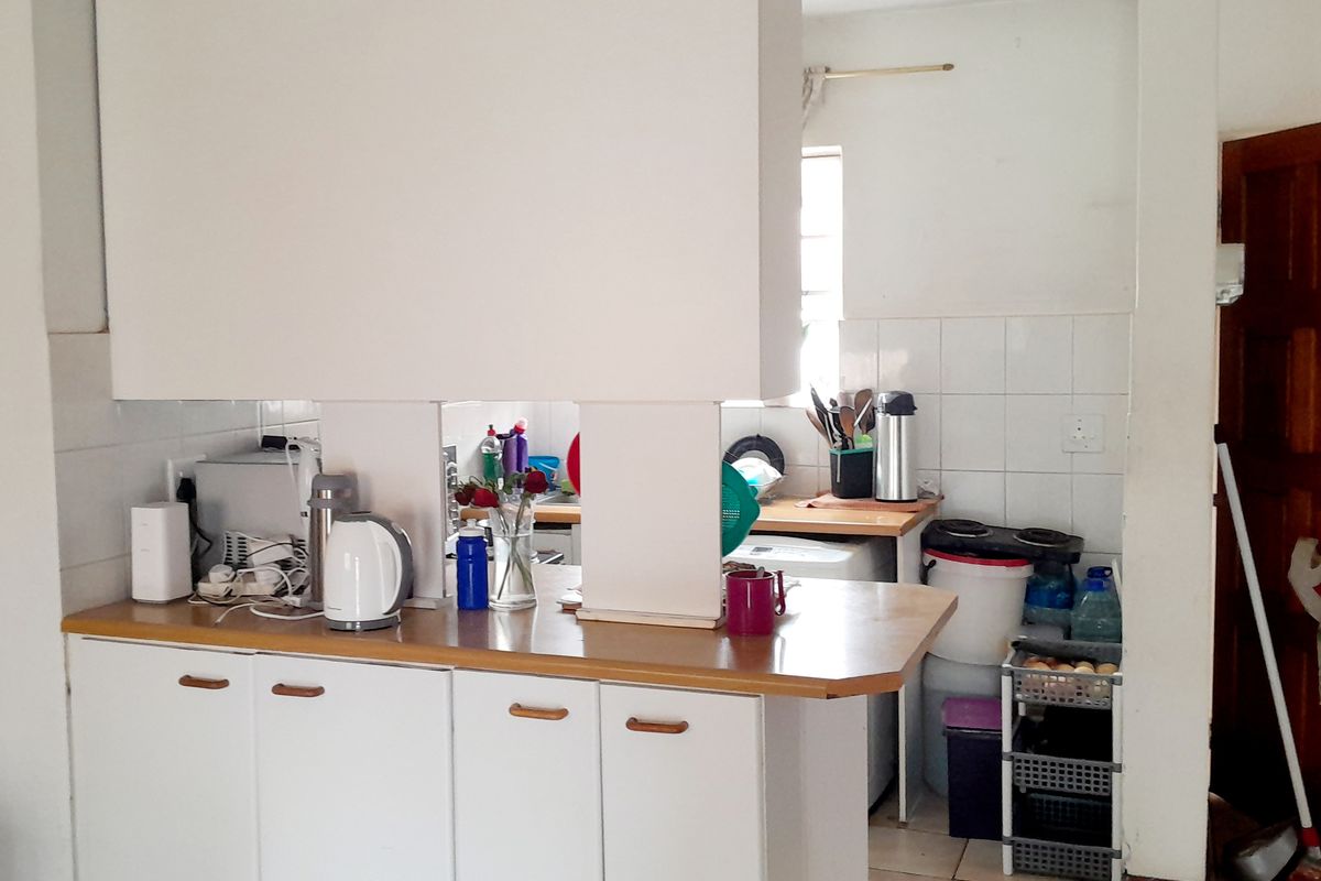 A functional kitchen area featuring laminate countertops, white cabinetry, and tiled splashbacks, offering a practical layout with potential for modern updates.