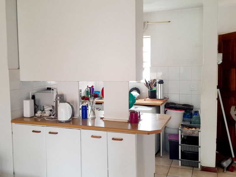 A functional kitchen area featuring laminate countertops, white cabinetry, and tiled splashbacks, offering a practical layout with potential for modern updates.