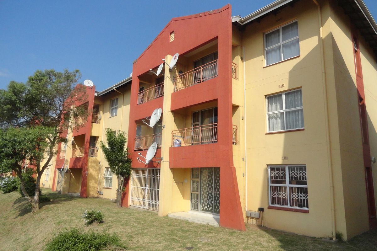 Exterior view of a multi-story apartment block featuring balconies, security gates, and satellite dishes on the rear facade.