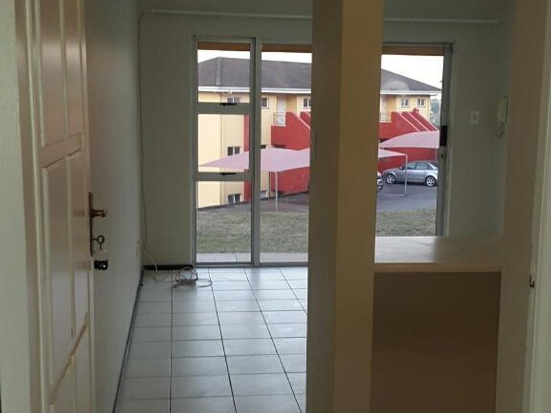 An empty open-plan living area featuring tiled flooring, a structural pillar, and a sliding glass door leading to the exterior.